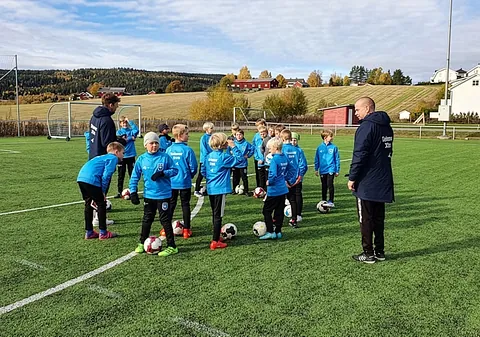 Unge telenor xtra spillere på fotballbanen med 2 trenere